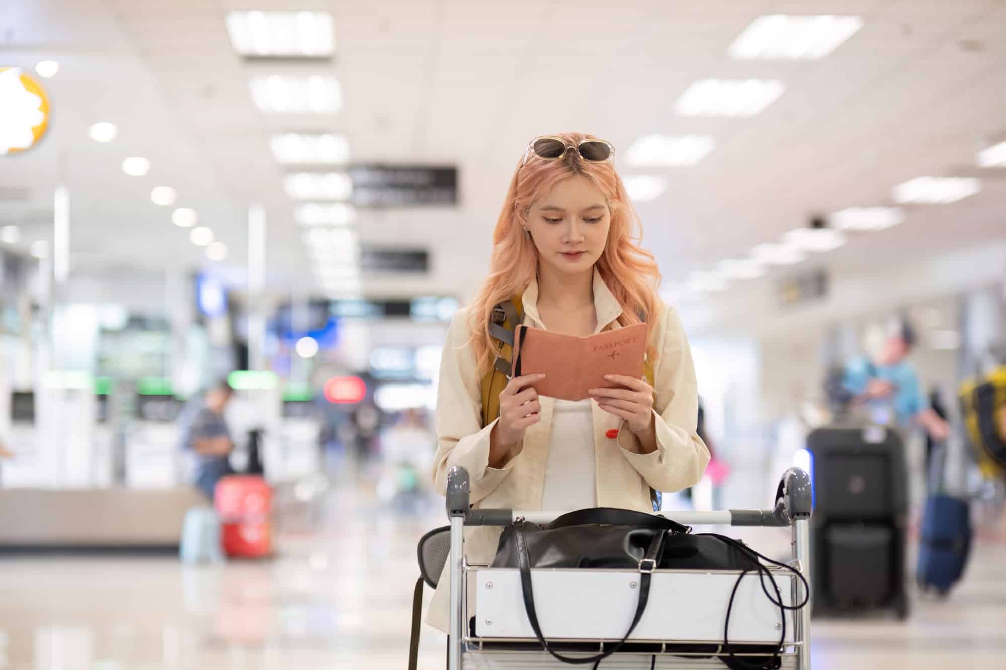 Woman holding passport in airport terminal. Concept of international travel and readiness